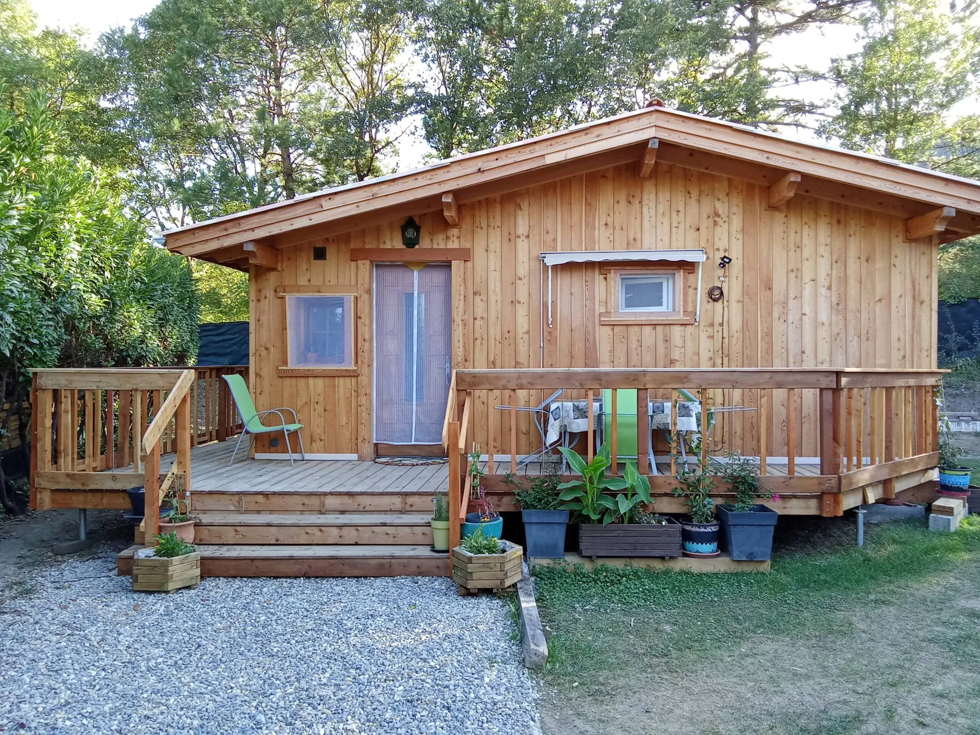 Façade du chalet, sa porte, ses fenêtres et ses plantes en pot