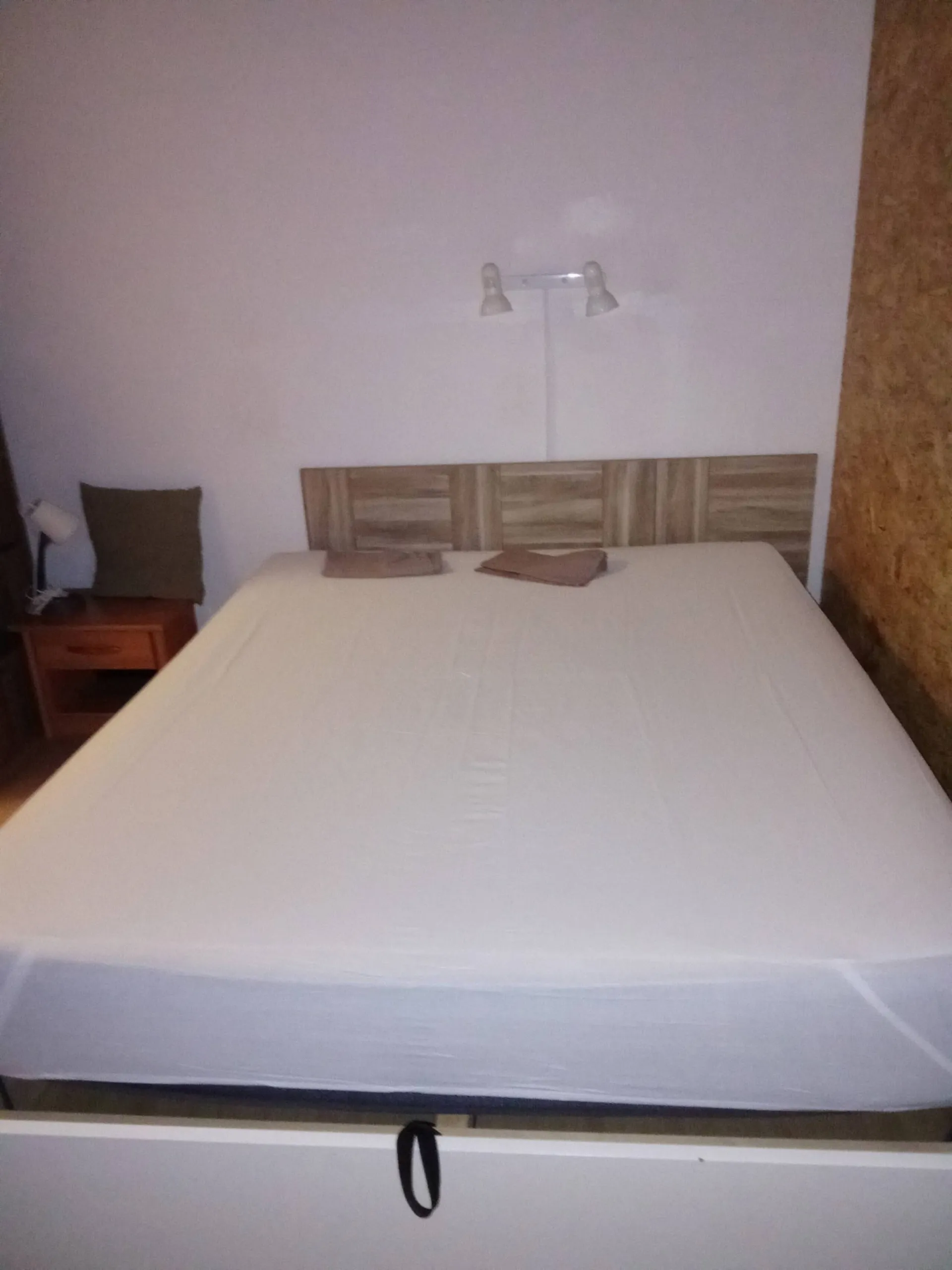 Le lit double dressé de blanc, tête de lit en bois