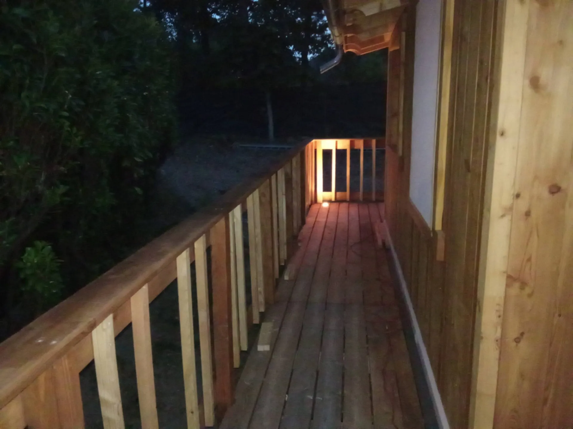 La coursive en bois qui longe le chalet, éclairée à la nuit tombée