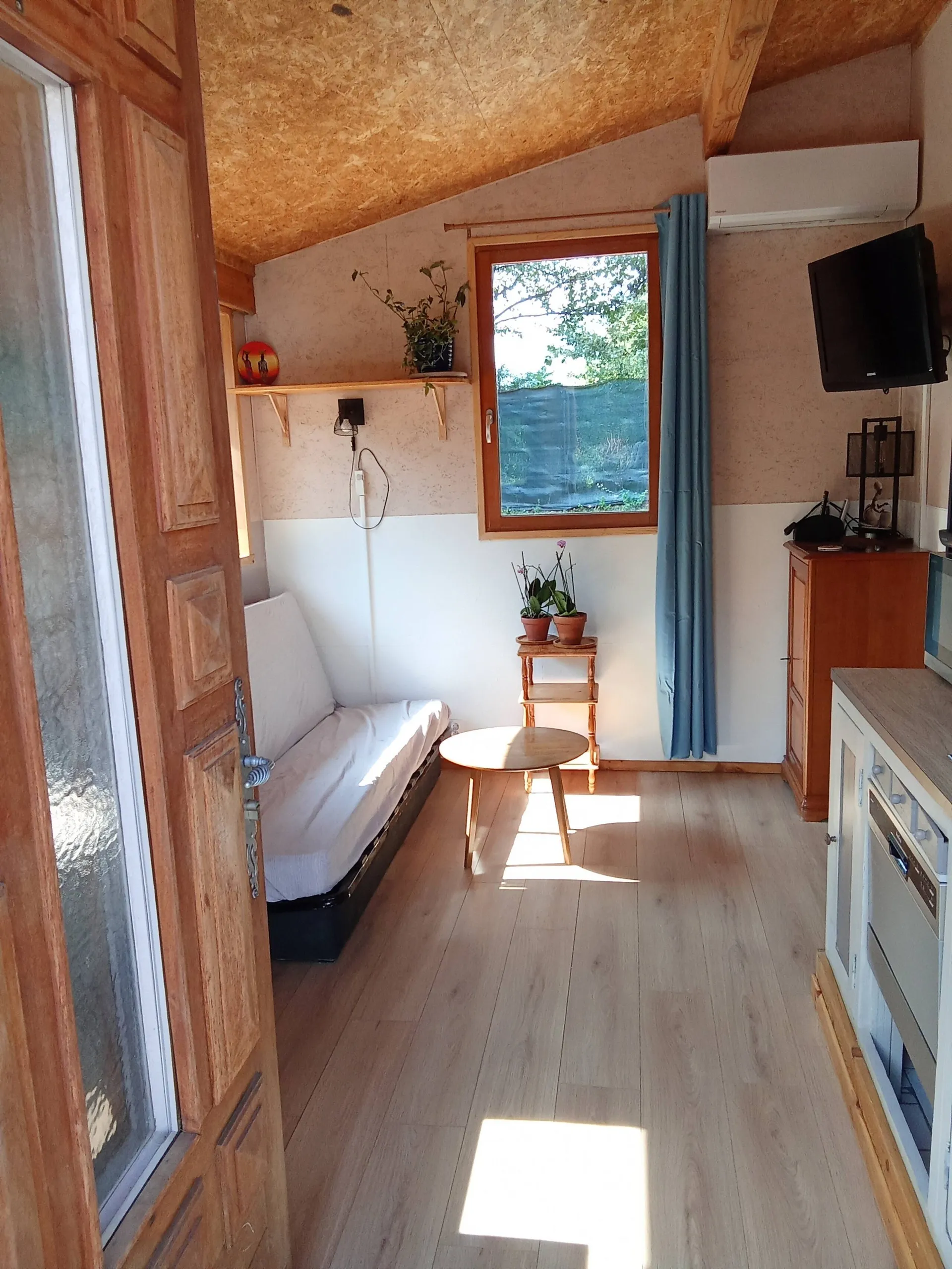 Le salon baigné de soleil, canapé blanc et table ronde en bois