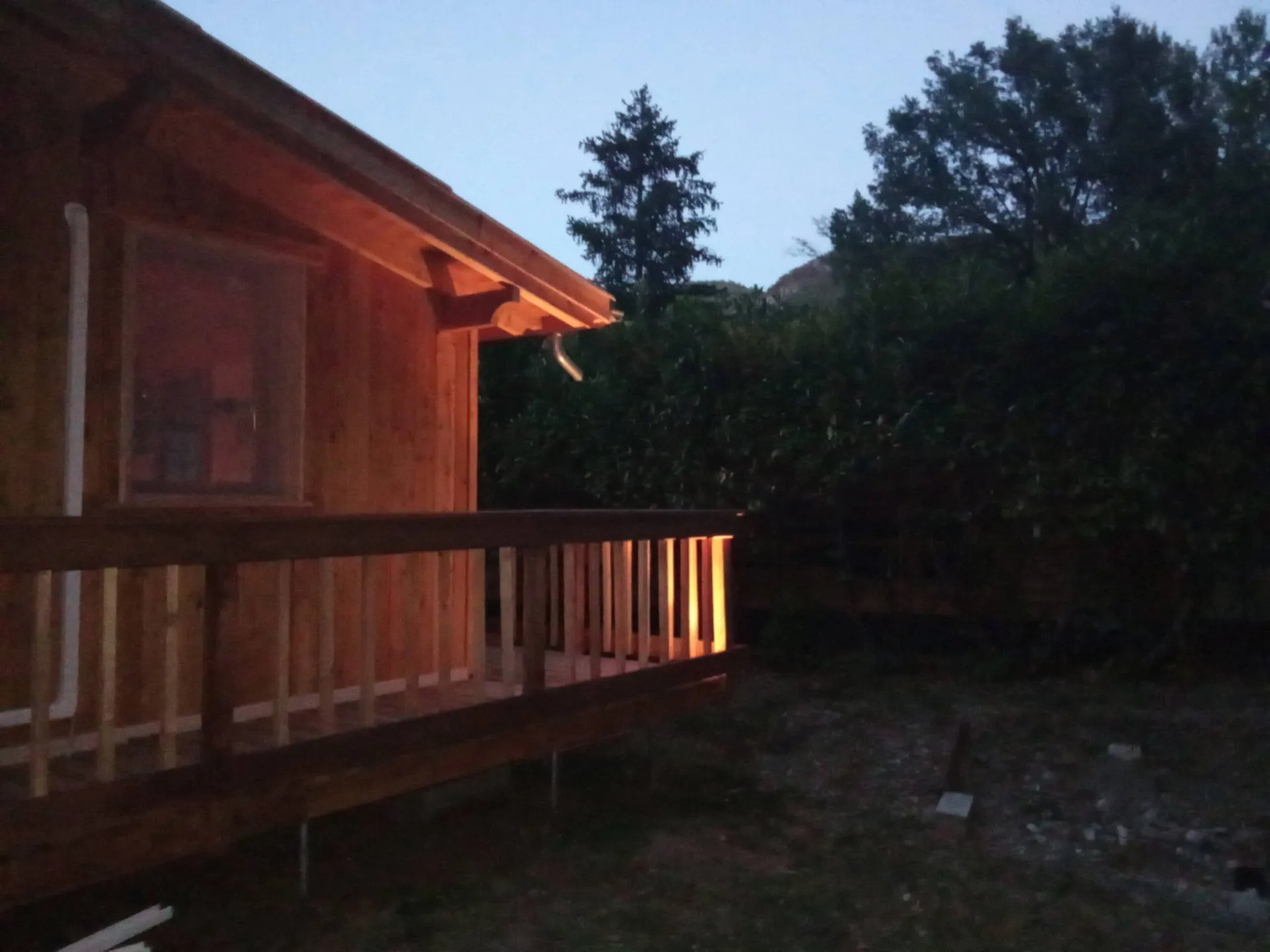 La terrasse illuminée au crépuscule, sous les grands arbres